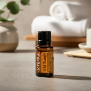 Olejek eteryczny Dzika Pomarańcza doTERRA na blacie z eukaliptusem i zwiniętym ręcznikiem