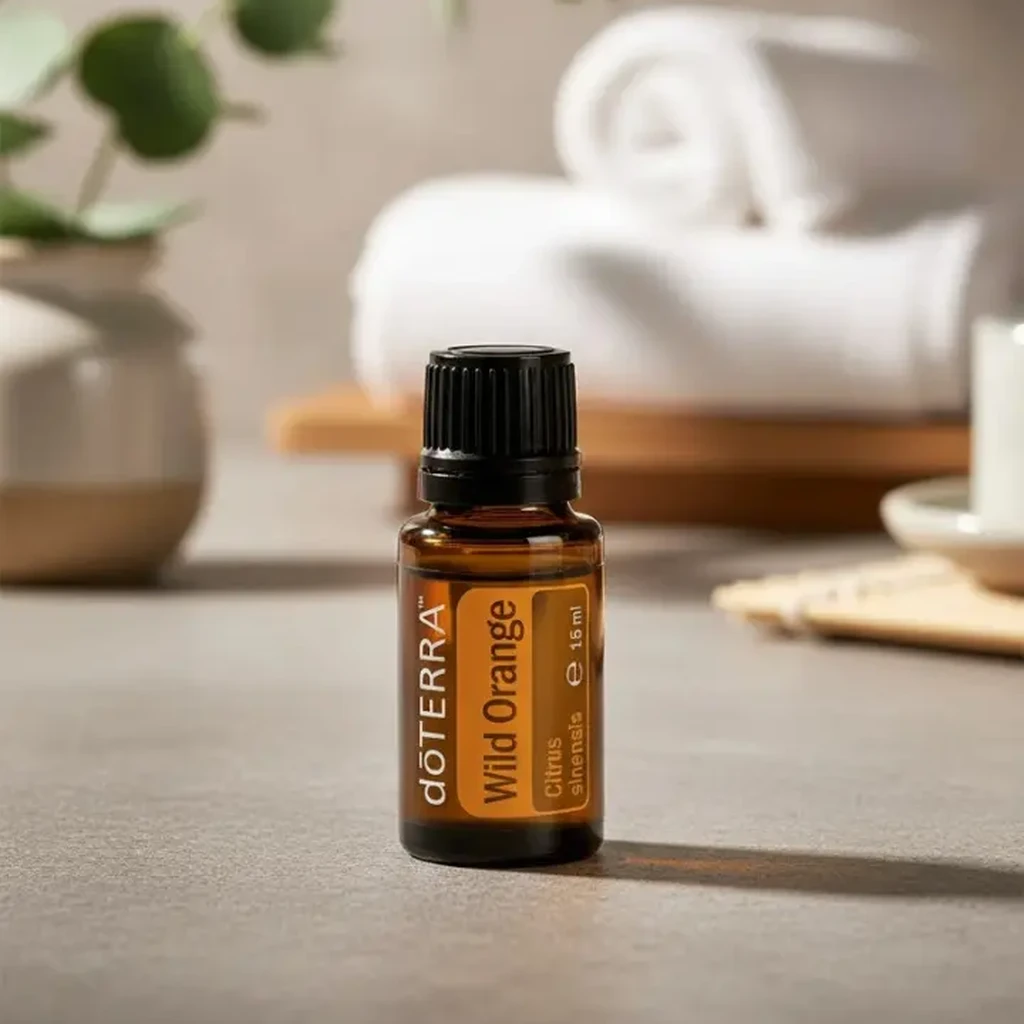 Olejek eteryczny Dzika Pomarańcza doTERRA na blacie z eukaliptusem i zwiniętym ręcznikiem