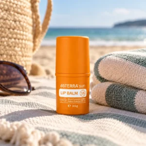 Mineralny balsam do ust doTERRA sun SPF 15 na plażowym ręczniku obok okularów i torby