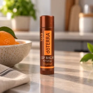 Sztyft balsamu do ust doTERRA Tropical na kuchennym blacie obok miski z pomarańczą