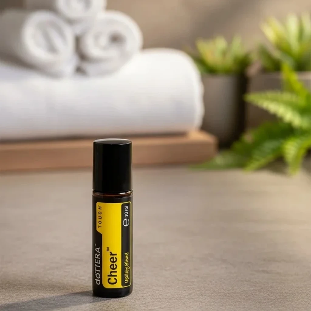 Cheer Touch doTERRA na kamiennej podstawce obok złożonych ręczników spa