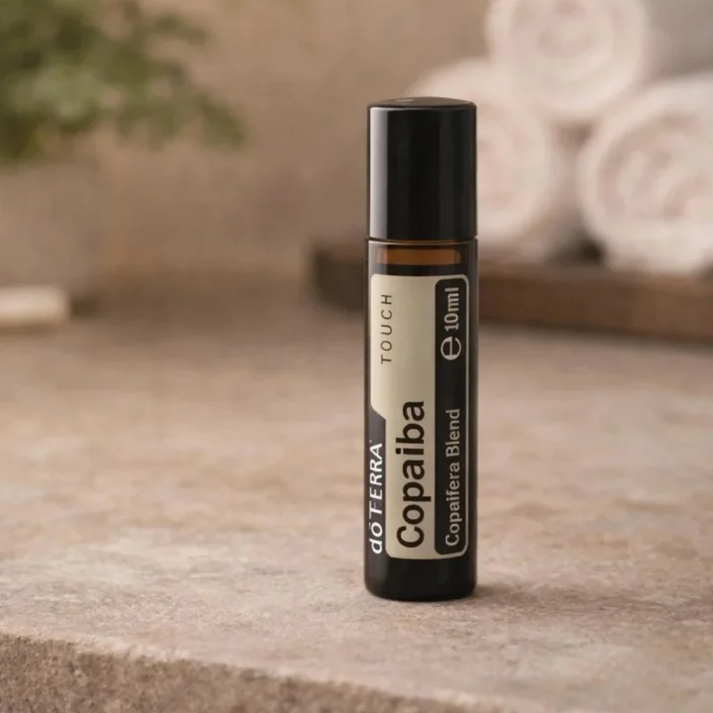 Copaiba Touch doTERRA na kamiennej podstawce obok złożonych ręczników spa