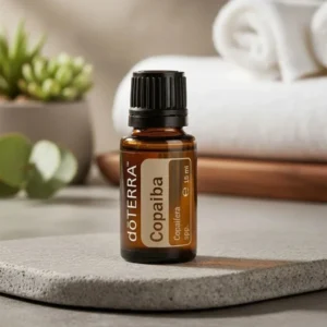 Copaiba doTERRA na kamiennej podstawce obok złożonych ręczników spa