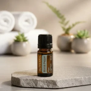 Czarny Pieprz doTERRA na kamiennej podstawce obok złożonych ręczników spa