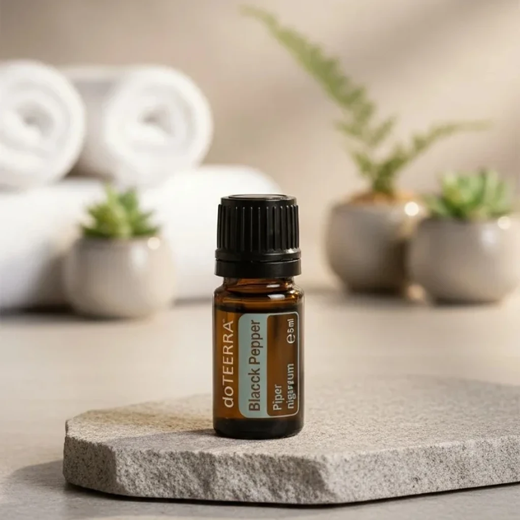 Czarny Pieprz doTERRA na kamiennej podstawce obok złożonych ręczników spa