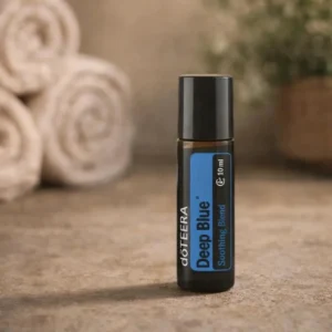 Deep Blue Roll-on doTERRA na kamiennej podstawce obok złożonych ręczników spa