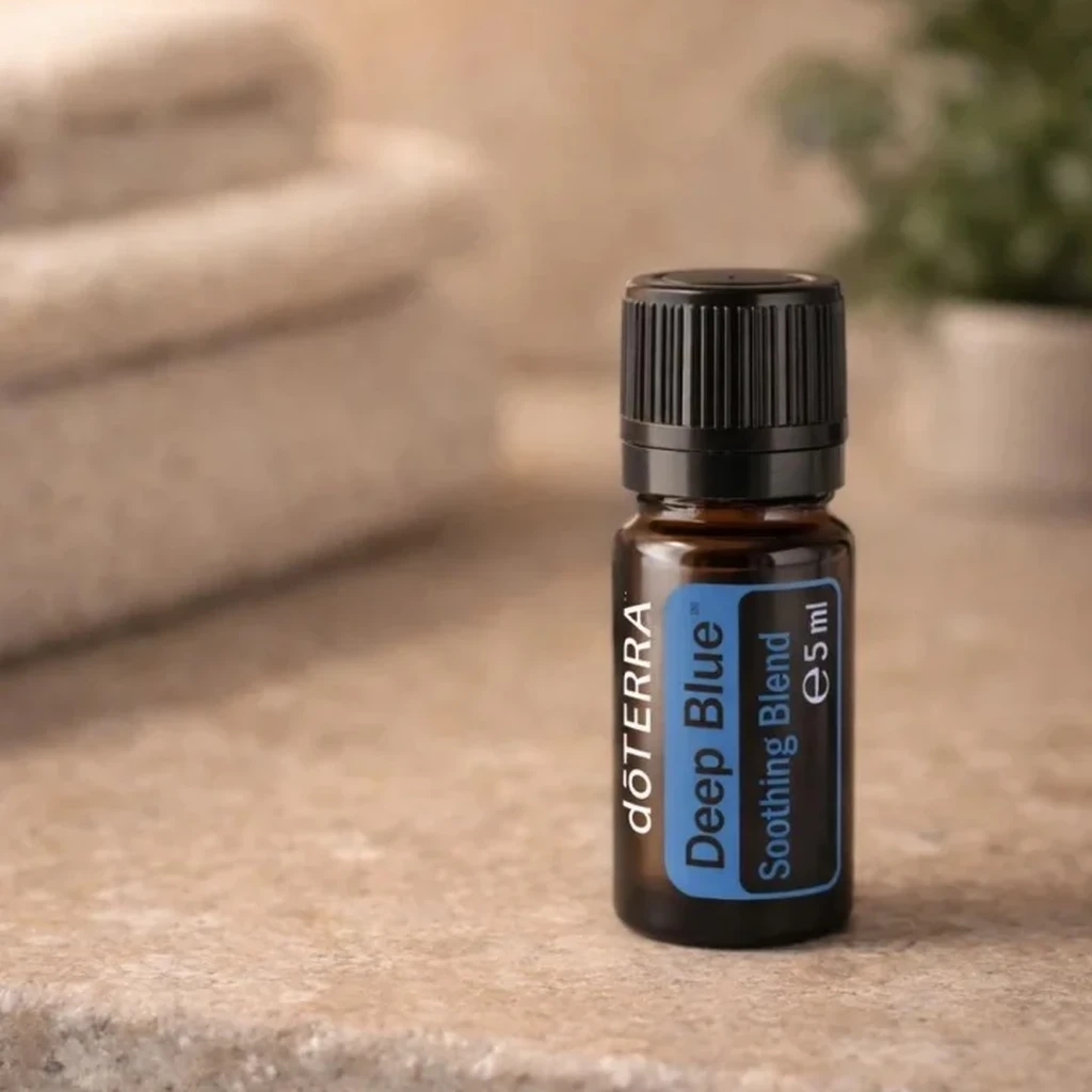 Deep Blue doTERRA na kamiennej podstawce obok złożonych ręczników spa