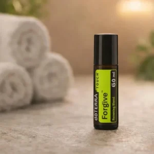 Forgive Touch doTERRA na kamiennej podstawce obok złożonych ręczników spa