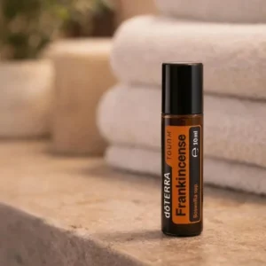 Frankincense Touch doTERRA na kamiennej podstawce obok złożonych ręczników spa