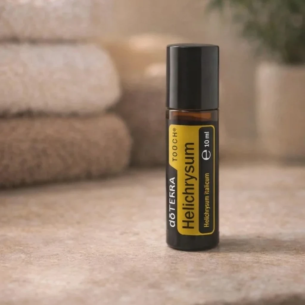 Helichrysum Touch doTERRA na kamiennej podstawce obok złożonych ręczników spa