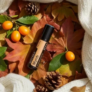 Myrrh Touch doTERRA na jesiennej dekoracji z liśćmi i szyszkami