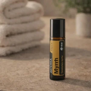 Myrrh Touch doTERRA na kamiennej podstawce obok złożonych ręczników spa