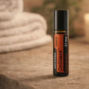 On Guard Touch doTERRA na kamiennej podstawce obok złożonych ręczników spa
