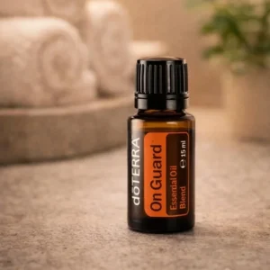 On Guard doTERRA na kamiennej podstawce obok złożonych ręczników spa