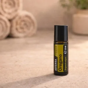 Oregano Touch doTERRA na kamiennej podstawce obok złożonych ręczników spa