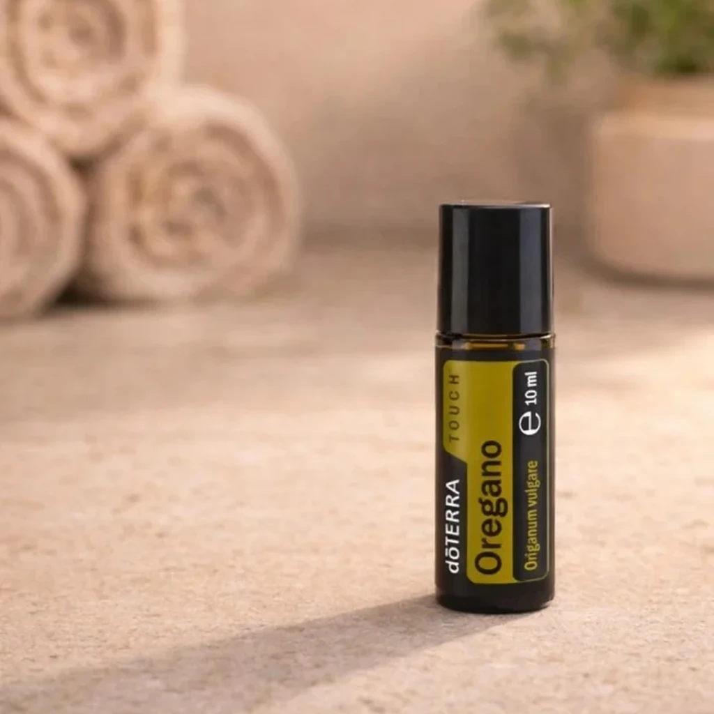 Oregano Touch doTERRA na kamiennej podstawce obok złożonych ręczników spa