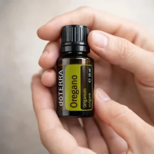 Dłonie trzymające Oregano doTERRA – aplikacja olejku