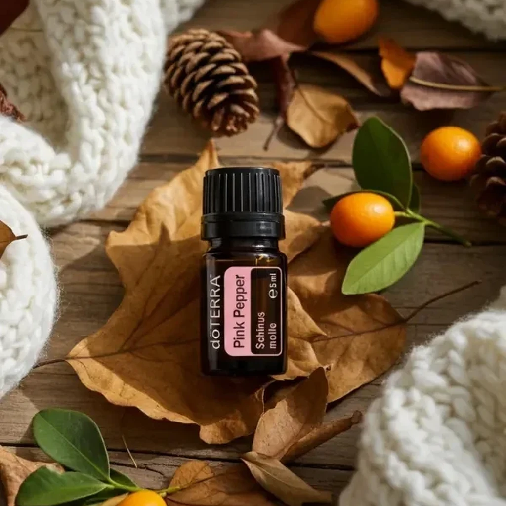 Pieprz Różowy doTERRA na jesiennej dekoracji z liśćmi i szyszkami