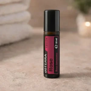 Rose Touch doTERRA na kamiennej podstawce obok złożonych ręczników spa