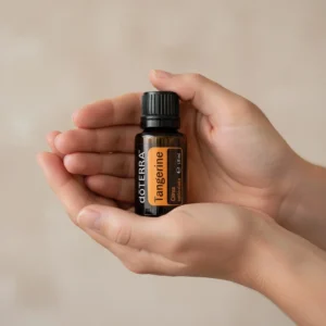 Dłonie trzymające Tangerynka doTERRA – aplikacja olejku