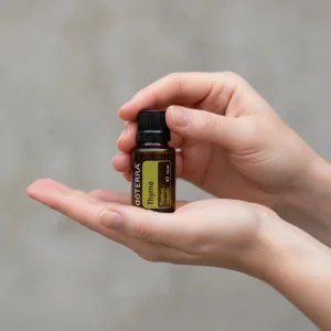 Dłonie trzymające Tymianek doTERRA – aplikacja olejku