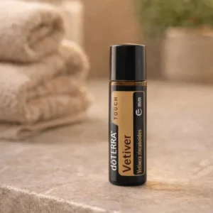 Vetiver Touch doTERRA na kamiennej podstawce obok złożonych ręczników spa