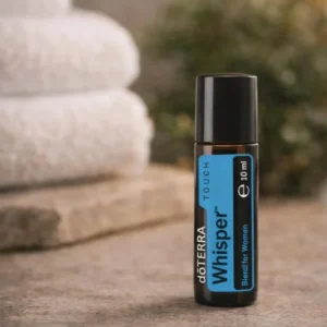 Whisper Touch doTERRA na kamiennej podstawce obok złożonych ręczników spa