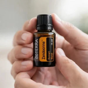Dłonie trzymające Zendocrine doTERRA – aplikacja olejku